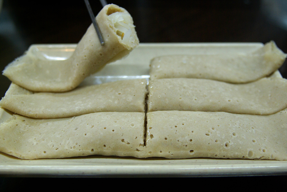 Jeju bingtteok buckwheat crepes rolled around seasoned shredded radish, served on a plate
