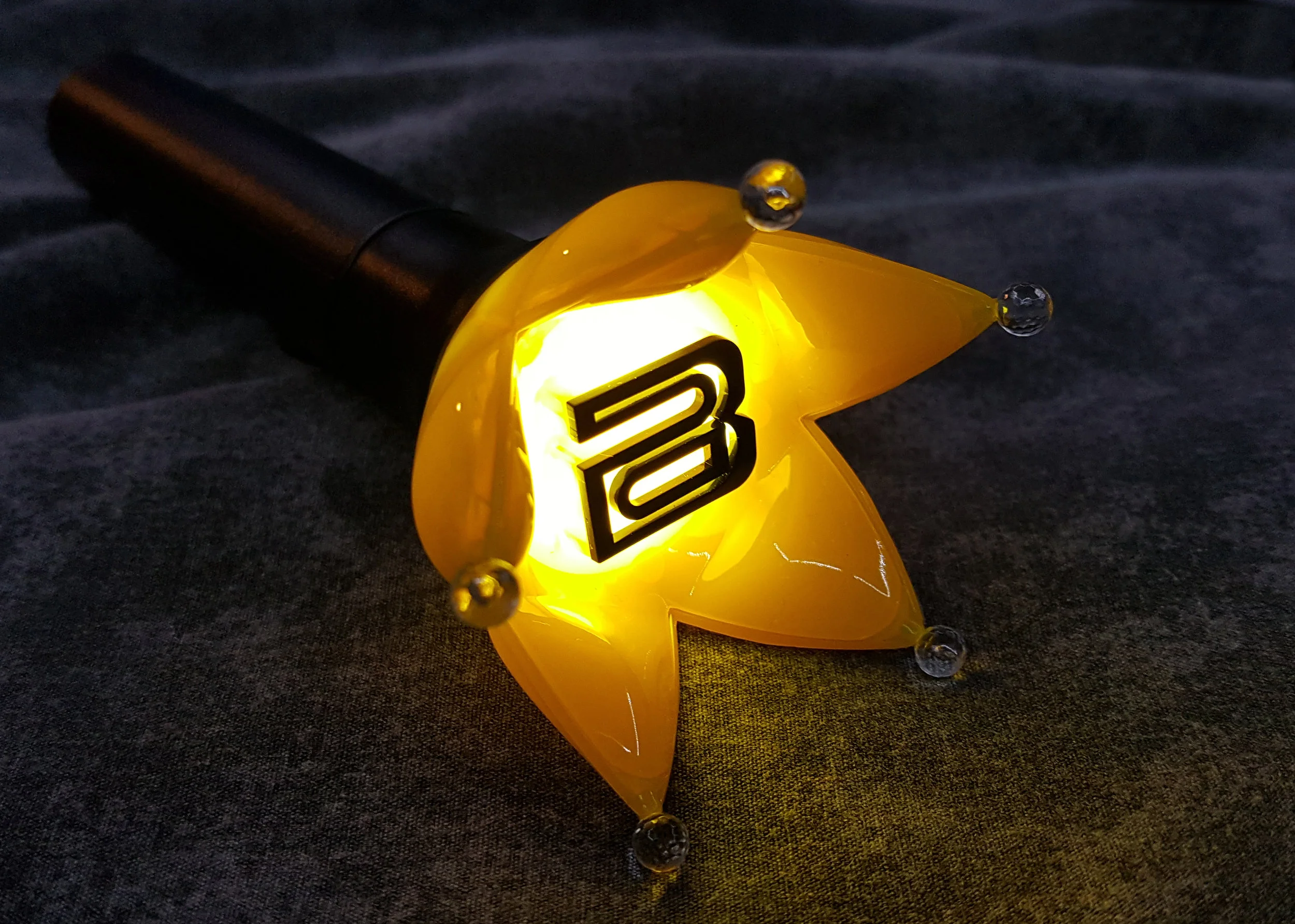 Lit yellow BIGBANG crown-shaped K-pop concert light stick shown as an example of official fan light sticks