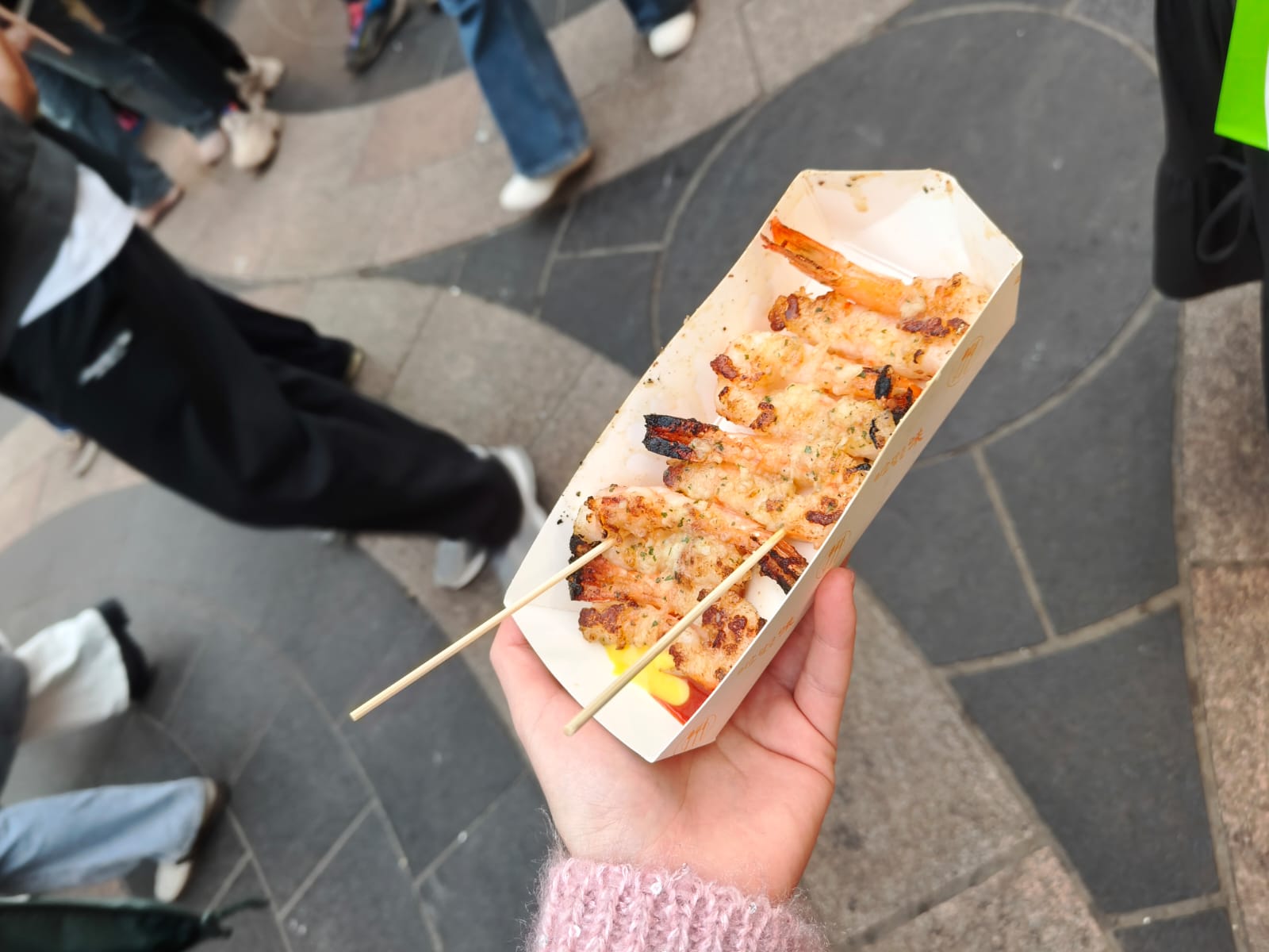 Grilled street food skewers in a paper tray being held by a visitor in Myeongdong, Seoul