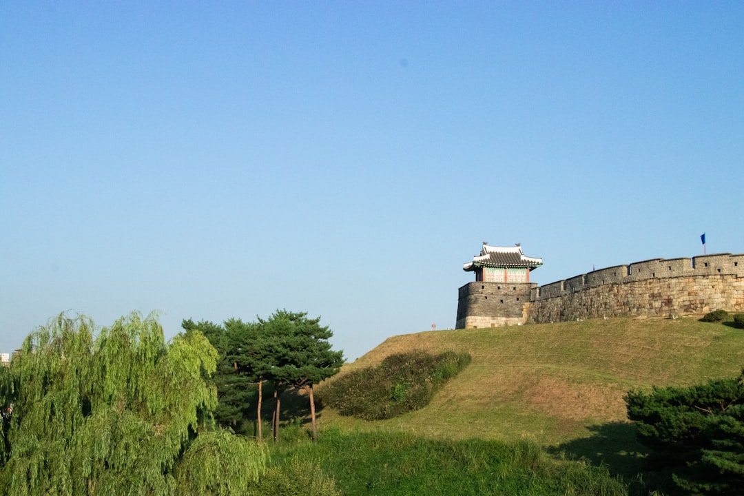 Suwon Hwaseong Fortress wall and pavilion above a grassy slope